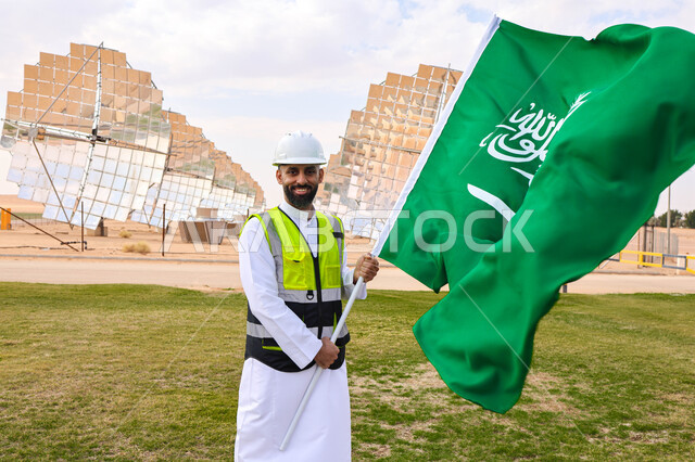 مهندس عربي خليجي سعودي يحمل علم المملكة، محطات الطاقة الشمسية، مستقبل الطاقة المتجددة، ألواح شمسية، اليوم الوطني السعودي 92، رؤية السعودية 2030