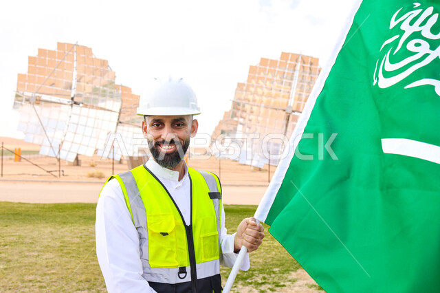 مهندس عربي خليجي سعودي يحمل علم المملكة، محطات الطاقة الشمسية، مستقبل الطاقة المتجددة، ألواح شمسية، اليوم الوطني السعودي 92، رؤية السعودية 2030