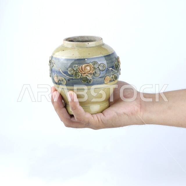 صوره مقربه ليد تحمل إناء  من الخزف, مزهريه, ديكورات وزينه, خلفية بيضاء ، أنتيكا وتحف خزفيه ، وعاء زجاجي