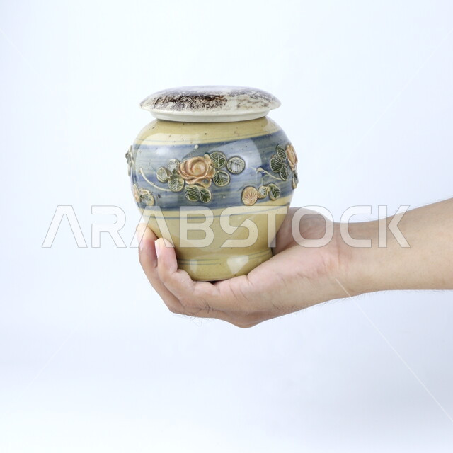 صوره مقربه ليد تحمل إناء  من الخزف, مزهريه, ديكورات وزينه, خلفية بيضاء ، أنتيكا وتحف خزفيه ، وعاء زجاجي