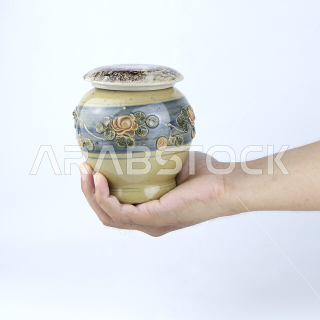 صوره مقربه ليد تحمل إناء  من الخزف, مزهريه, ديكورات وزينه, خلفية بيضاء ، أنتيكا وتحف خزفيه ، وعاء زجاجي
