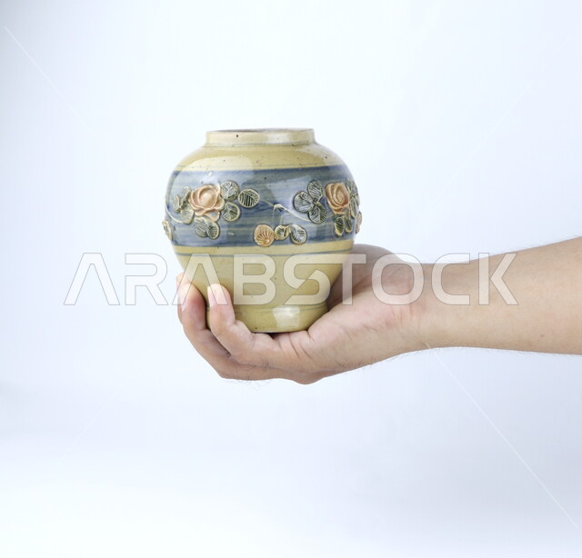 صوره مقربه ليد تحمل إناء  من الخزف, مزهريه, ديكورات وزينه, خلفية بيضاء ، أنتيكا وتحف خزفيه ، وعاء زجاجي
