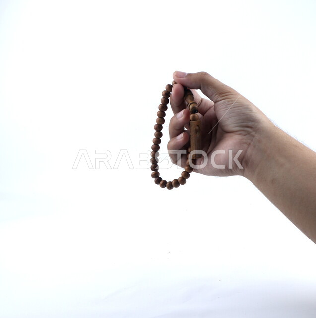 صورة مقربة ليد تمسك السبحه، التسبيح وذكر الله تعالى، الإستغفار والدعاء، العبادة والتقرب الى الله، إسلاميات وعبادة، خلفيه بيضاء