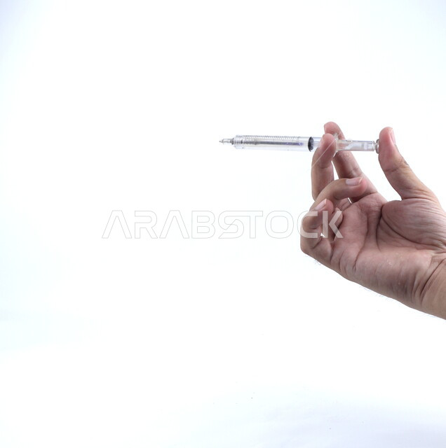 صورة مقربة ليد تمسك إبره طبيه، تطعيم، تجهيز الحقنة، معدات وأدوات طبية, لقاح طبي ، خلفيه بيضاء