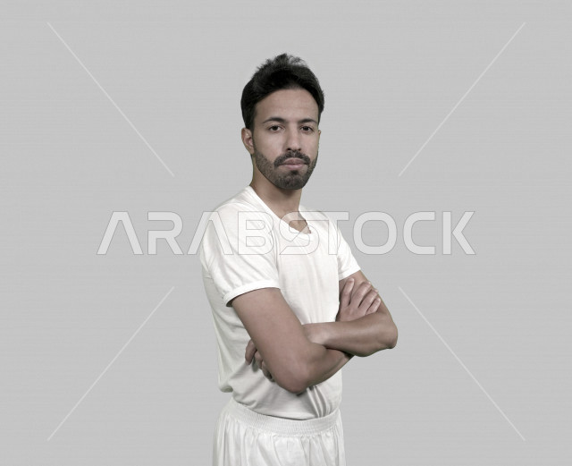 بورتريه شاب سعودي يرتدي سروال وفانيلة، رجل عربي خليجي بملابس الثوب الداخلية بخلفية بيضاء