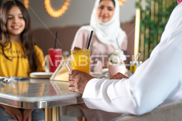 A unique and unique family session, gestures indicating amazement and joy, a Saudi Arabian Gulf family sitting with her mother in a café, spending quality times with children, cafes and restaurants in Saudi Arabia