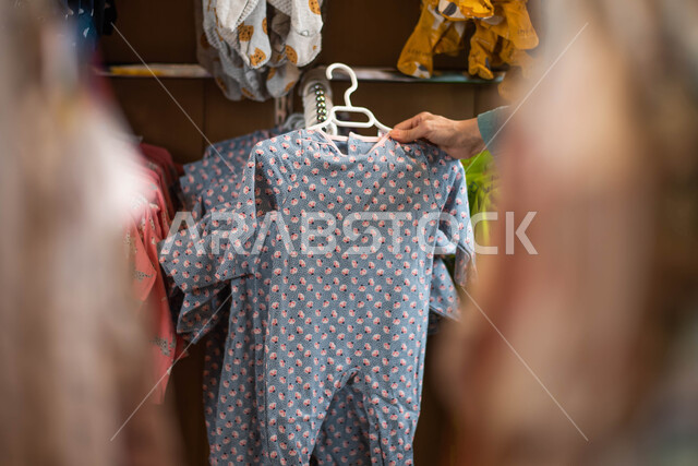 صوره مقربه لملابس اطفال في متجر الملابس ، اختيار الملابس المناسبه ، ملابس نوم للأطفال،  الاستمتاع بالعروض والتخفيضات ، التسوق في المول التجاري ،اختيار ملابس مواليد, شراء ثياب للأطفال الرضع ، الجمعة البيضاؤ