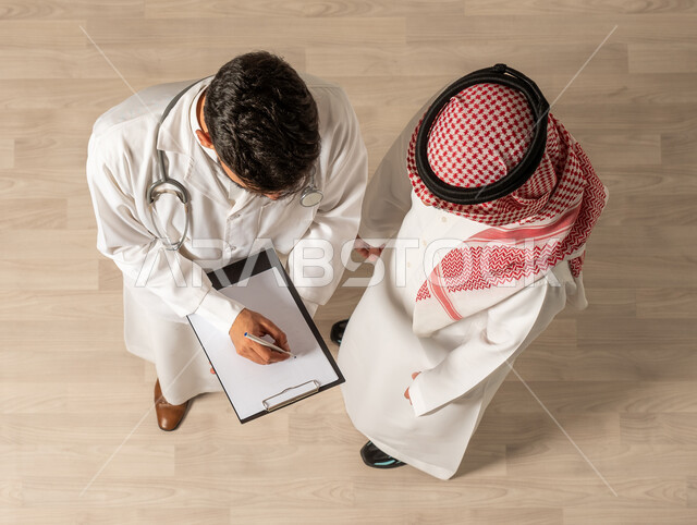 The concept of the medical profession, writing and recording medical reports and health cases. A Saudi Arabian Gulf man shakes hands with a Saudi Arab Gulf doctor, Saudi Arabian Gulf jobs, hospitals and health centers, greetings and peace