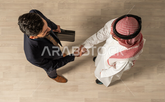  تعارف وصداقة ، مهن ووظائف السعودية ، صوره علويه عاموديه لرجل عربي سعودي خليجي يرتدي الزي السعودي التقليدي  ورجل عربي يرتدي البدله الرسميه ، التحية والسلام ، التصافح في مقر الشركة ، لقاء الأصدقاء  ، صفقة عمل ناجحة