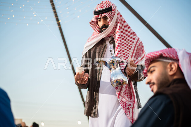 جلسة عربية شعبية، اصدقاء عرب خليجيين سعوديين يستمتعون برحلة تخييم برية في الصحراء، تقديم القهوة الساخنة للضيوف، حسن الضيافة والإستقبال، دلة قهوة عربية، خيام في صحاري السعودية، كشتة برية  شبابية