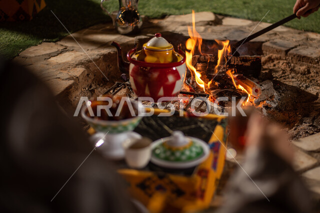 الاستمتاع بالمشروبات الساخنة في الأجواء الشتوية، صورة مقربة لرجل سعودي عربي خليجي يستمتع بشرب الشاي، رحلة تخييم في صحاري السعودية، حسن الكرم والضيافه عند العرب،  الكشتات البرية العربية الشعبية المسائية، الجلسات الهادئة في البراري أمام موقد النار