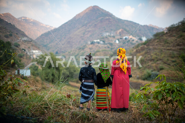 A back view of children standing in the middle of nature in the Fifa Mountains in Jizan, Saudi Arabia, green mountain nature in Jizan, coffee plantations, nature background