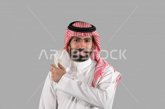 بورتريه لشاب عربي خليجي سعودي يقوم بإزالة الكمامة الواقية، اتخاذ اجراءات الوقاية من فايروس كورونا (كوفيد-19)، خلفية بيضاء