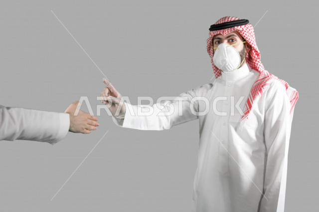 بورتريه لشاب عربي خليجي سعودي يرتدي الكمامة والقفازات، اتخاذ اجراءات الوقاية من فايروس كورونا (كوفيد-19)، شاب يرفع اصبعة السبابة ويرفض المصافحة، تجنب انتشار العدوى، خلفية بيضاء
