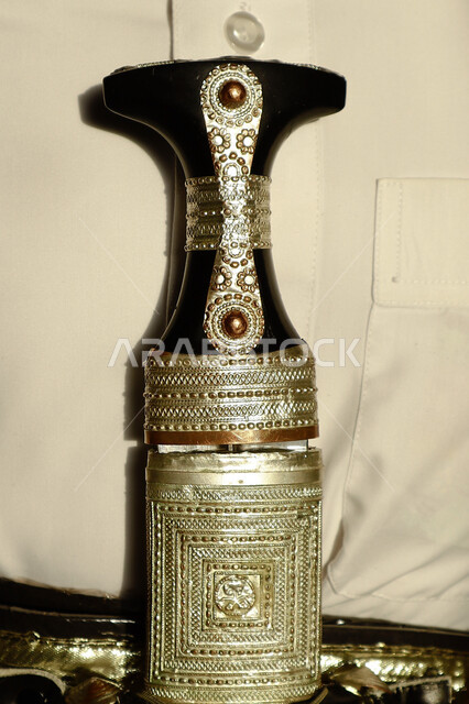 صورة مقربة لخنجر سعودي  تقليدي مزخرف بالفضة ، المحزم والثوب, زي تراثي شعبي تقليدي 