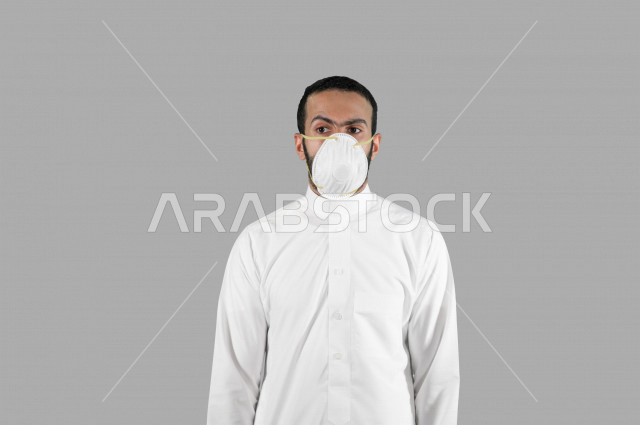 Portrait of a Saudi Arabian Gulf youth, wearing a protective mask, taking measures to prevent corona virus (Covid-19), different face and hand gestures, white background