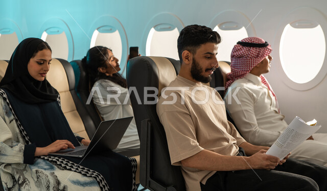 مجموعة من الركاب العرب الخليجيون السعوديون في الطائرة ، الخطوط الجوية السعودية ، سياحة وسفر ، انجاز مهام العمل عبر الحاسوب المحمول ، الاستمتاع بالقراءة على متن الطائرة ، رحلة عمل .