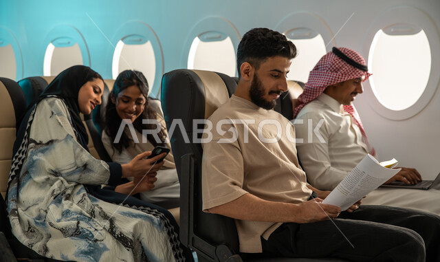 قراءة الكتب المفيدة للتعلم والتثقف ، مجموعة من الركاب العرب الخليجيون السعوديون في مقصورة الطائرة ، ممارسة هواية القراءة ،  قضاء أوقات ممتعة برفقة الاصدقاء  ، رحلة عمل ، خطوط الطيران السعودي.