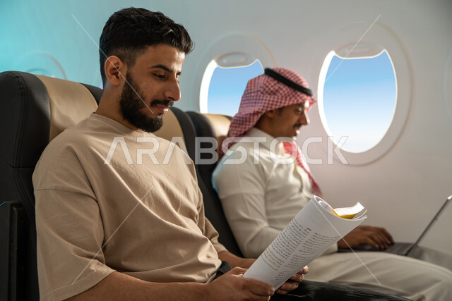   رجال أعمال  عرب خليجيون سعوديون في مقعد الطائرة ، الاستمتاع بالقراءة على متن الطائرة ، رحلة عمل ، الخطوط الجوية السعودية  ، انجاز مهام العمل عبر  جهاز الحاسوب  المحمول ، درجة رجال الاعمال .