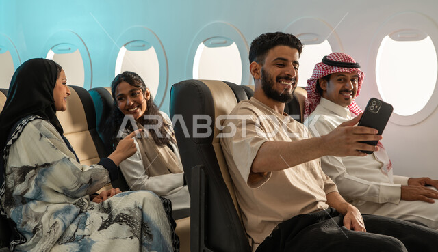 رحلات سياحية جويه ممتعة  ، مجموعة من الركاب العرب السعوديون الخليجيون في الطائرة ، التقاط صور تذكارية داخل مقصورة  الطائرة ،  الخطوط الجوية السعودية ، رحلة سياحية شبابية ، ايماءات تدل على السعادة.
