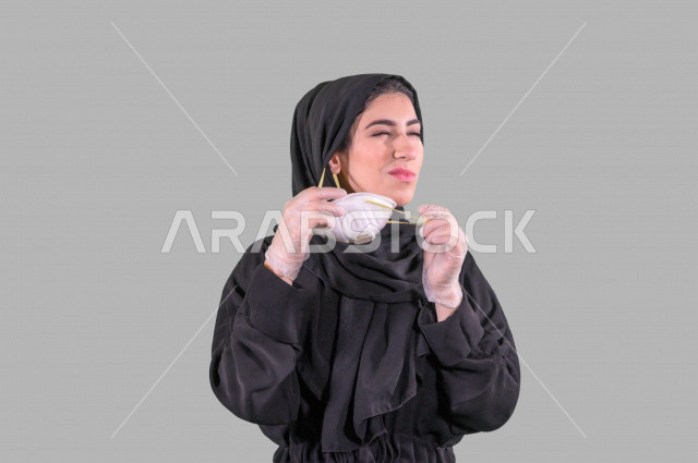 بورتريه لمرأة عربية خليجية سعودية ترتدي بيدها قفازات وتقوم بإزالة الكمامة الواقية، اتخاذ اجراءات الوقاية من فايروس كورونا (كوفيد-19)، خلفية بيضاء