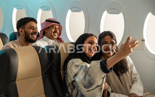  شباب وبنات عرب خليجيون سعوديون على متن الطائرة ، قضاء أوقات ممتعة برفقة الاصدقاء ، التقاط صور تذكارية باستخدام الهاتف المحمول ، الخطوط الجوية السعودية ، رحلات سياحية جماعية .