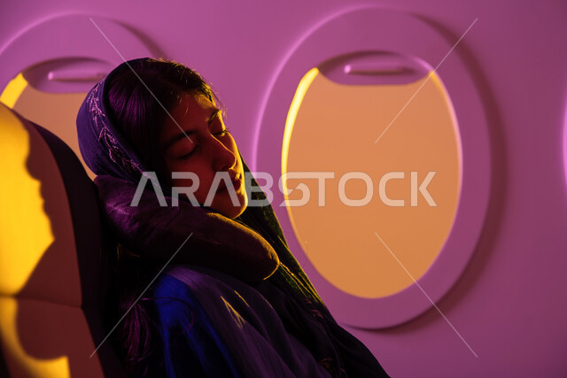 خطوط الطيران الجوي ، الشعور بالتعب والارهاق, صورة مقربة لامرأة عربية خليجية سعودية محجبة ترتدي العباءه الخليجية داخل مقصورة الطائرة ، ايماءات تدل على النوم والاسترخاء, وسائل مواصلات جوية ، سياحة وسفر ، رحلات جوية سياحية.
