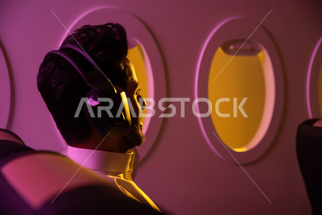 تقنية الهيدفون الحديثة, رحلات جوية سياحية, عطلة صيفية سعيدة, صورة من الخلف لرجل عربي خليجي سعودي يرتدي سماعه الرأس و يجلس في مقعد الطائرة, الخطوط الجوية السعودية, سياحة وسفر, رحلة عمل .