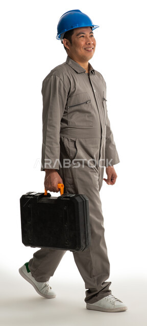 Portrait of a Filipino construction worker with facial gestures and hands indicating movement, an architect wearing a protective helmet and carrying a tool bag in his hand, walking and moving forward, a hand tool bag, finishing tools, recruiting labor fro