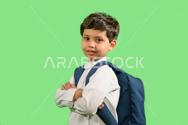 كروما لطالب مدرسي عربي خليجي سعودي يرتدي حقيبة ظهر مدرسية، ارتداء الزي المدرسي التقليدي، ايماءات وجه ويدين تدل على السعادة، خلفية خضراء