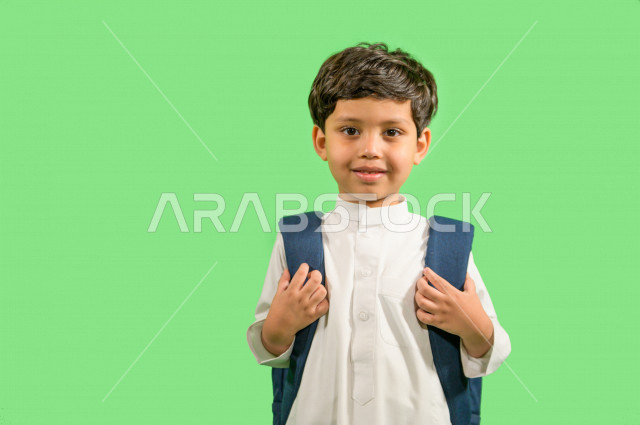 كروما لطالب مدرسي عربي خليجي سعودي يرتدي حقيبة ظهر مدرسية، ارتداء الزي المدرسي التقليدي، ايماءات وجه ويدين تدل على السعادة، خلفية خضراء