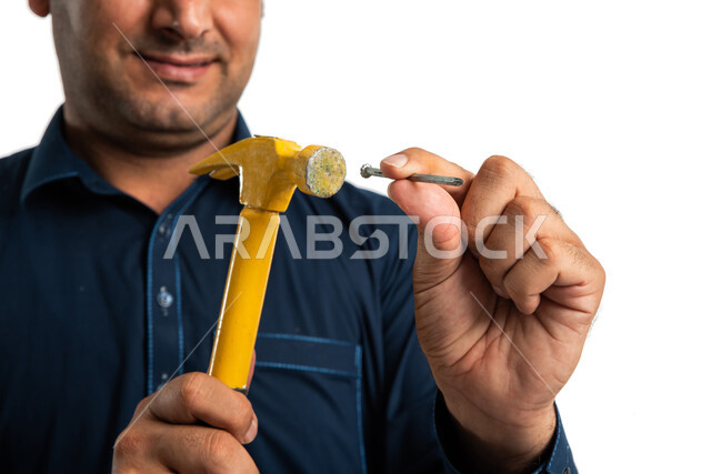 بورتريه لعامل بناء باكستاني يمسك مسمار ومطرقة معدنية ويرتدي الزي الباكستاني التقليدي، ادوات البناء والنجارة، مقبض بلاستيكي، شاكوش، مهندس معماري، ادوات التشطيب، استقدام العمالة من الخارج، خلفية بيضاء