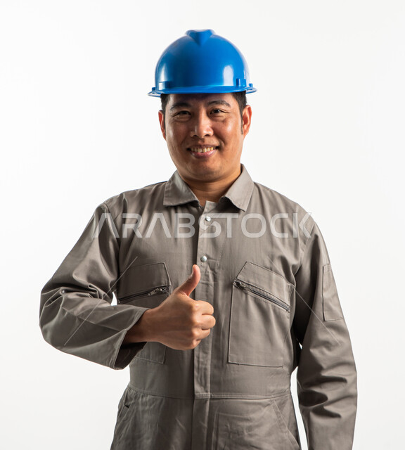 Portrait of a Filipino architect wearing a protective helmet and raising the thumb up, construction worker, face and hand gestures indicating admiration, acceptance and satisfaction, recruiting labor from abroad, white background