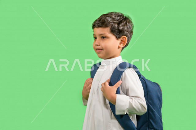 كروما لطالب مدرسي عربي خليجي سعودي يرتدي حقيبة ظهر مدرسية، ارتداء الزي المدرسي التقليدي، ايماءات وجه ويدين تدل على السعادة، خلفية خضراء