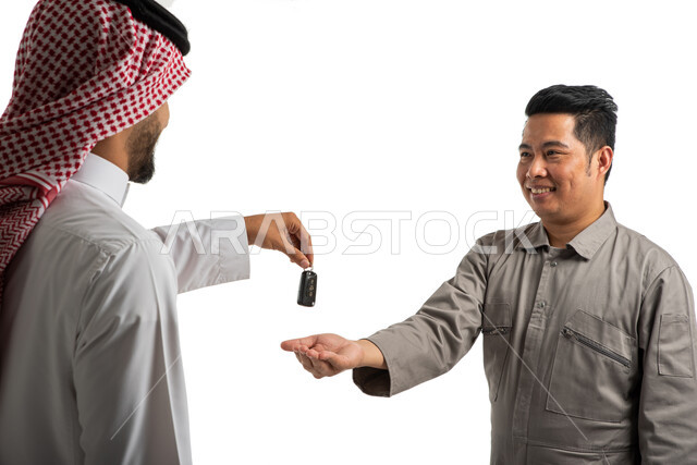 بورتريه لمهندس ميكانيكي فلبيني، استلام وتسليم مفاتيح السيارة، عميل سعودي خليجي يرتدي الزي السعودي التقليدي، وكالات وورش السيارات في السعودي، عامل صيانة سيارات، خدمات اصلاح وصيانة السيارات، استقدام العمالة من الخارج، خلفية بيضاء
