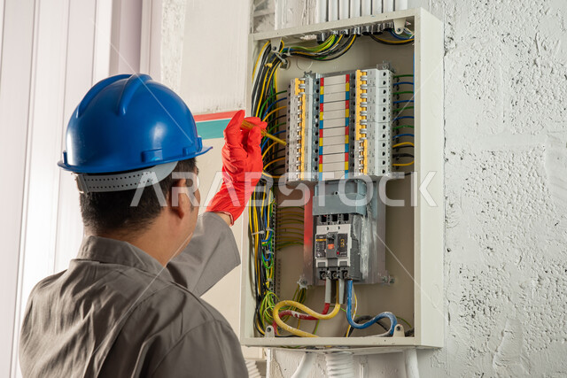 عامل صيانة كهربائي يستخدم مفك فحص الكهرباء، ارتداء قفازات العزل الكهربائي وخوذة الحماية، صيانة وتركيب لوحة عداد الكهرباء، مفهوم الهندسة الكهربائية، تركيب مفاتيح الكهرباء، عمل فني كهربائي، تمديد اسلاك الكهرباء، استقدام العمالة من الخارج