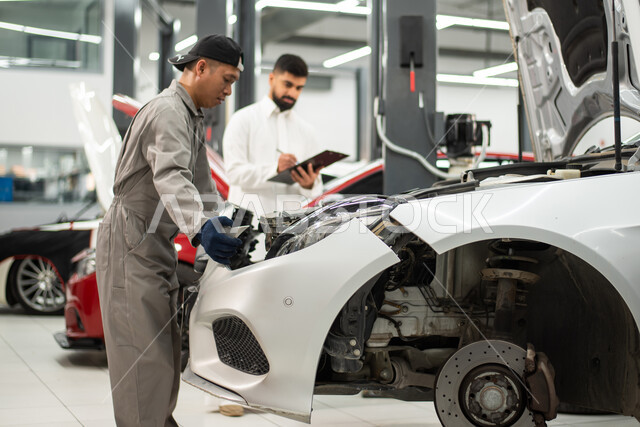  مهندس ميكانيكي محترف, تسجيل و تدوين الملاحظات , ورش ومعامل الصيانه في المملكه العربيه السعوديه, صوره مقربه لعامل صيانه فلبيني يقوم بإصلاح سيارة عميل عربي سعودي خليجي في الورشه, التشييك وتصليح السيارات في مركز الصيانه