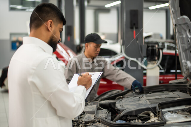  تسجيل و تدوين الملاحظات , ورش ومعامل الصيانه في المملكه العربيه السعوديه, صوره مقربه لعامل صيانه فلبيني يقوم بإصلاح سيارة عميل عربي سعودي خليجي في الورشه, التشييك وتصليح السيارات في مركز الصيانه, مهندس ميكانيكي محترف