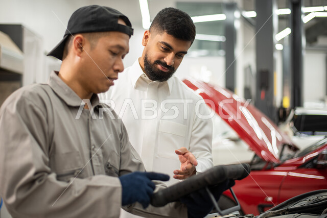 نقاش و حوار بين عامل صيانه  ميكانيكي  ورجل عربي سعودي خليجي حول تصليح أعطال اجزاء السياره، استخدام جهاز تقني متطور لاكتشاف العطل, أعمال الصيانه و الفحص والتشييك على أجزاء السياره, الاشارة الى شيئ ما, ورش ومعامل الصيانه في المملكه العربيه السعوديه