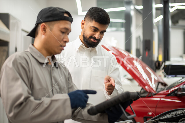 استخدام جهاز تقني متطور لاكتشاف العطل, حوار ونقاش بين عامل صيانه  ميكانيكي  ورجل عربي سعودي خليجي حول تصليح أعطال اجزاء السياره، أعمال الصيانه و الفحص والتشييك على أجزاء السياره, الاشارة الى شيئ ما, ورش ومعامل الصيانه في المملكه العربيه السعوديه