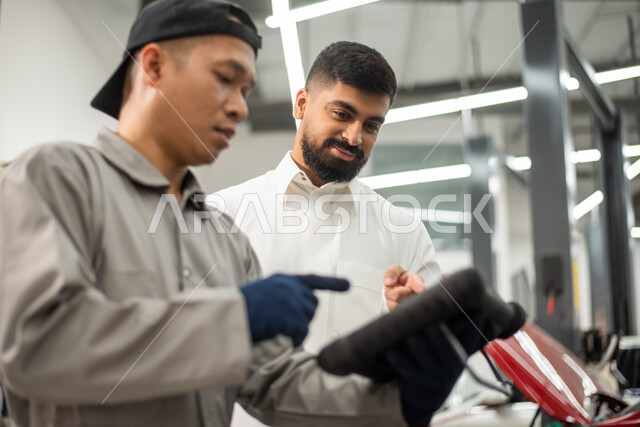 حوار ونقاش بين عامل صيانه  ميكانيكي  ورجل عربي سعودي خليجي حول تصليح أعطال اجزاء السياره، استخدام جهاز تقني متطور لاكتشاف العطل, أعمال الصيانه و الفحص والتشييك على أجزاء السياره, الاشارة الى شيئ ما, ورش ومعامل الصيانه في المملكه العربيه السعوديه