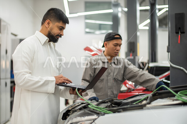 Car repair request via laptop, close-up of a maintenance worker repairing a Saudi Arabian Gulf customer's car in the workshop, gestures indicating satisfaction and acceptance of the workshop's services, checking and repairing cars in the maintenance cente