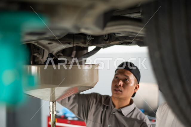 مهندس ميكانيكي في مركز فحص السيارات يقوم بالصيانه الدوريه ,صوره مقربه لعامل صيانه فلبيني يقوم بإصلاح سيارة  في الورشه,أعمال الصيانه و الفحص والتشييك على أجزاء السياره, ورش ومعامل الصيانه في المملكه العربيه السعوديه