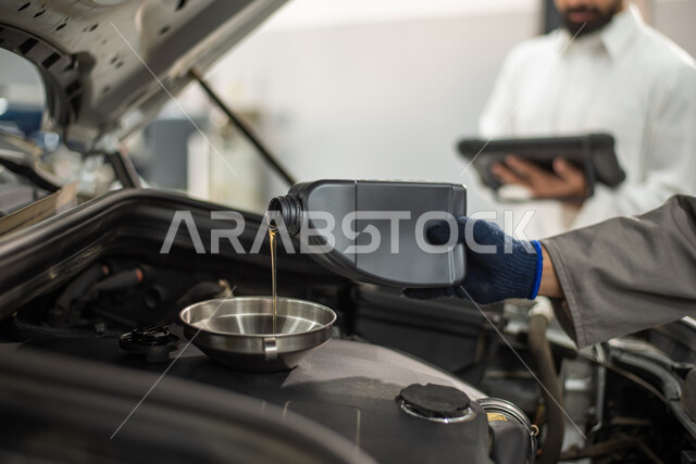  ورش ومعامل الصيانه في المملكه العربيه السعوديه, طلب تصليح السيارة عن طريق جهاز التابلت, صوره مقربه لعامل صيانه ميكانيكي يقوم بتغيير زيت السياره في الورشه, أعمال الصيانه و الفحص والتشييك على أجزاء السياره, مهندس ميكانيكي في مركز فحص السيارات يقوم بالصيانه