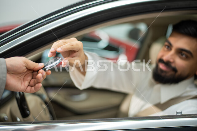 ايماءات تدل على القبول والرضى عن الخدمات الراقية و المتميزة, سائق عربي سعودي خليجي مبتسم ارتداء الثوب السعودي التقليدي يجلس في السياره  يقوم بتسليم مفتاح السيارة لعامل الصيانة,  خدمات اصلاح وصيانة السيارات في الورشه, مركز الصيانه وتصليح وسائل المواصلات