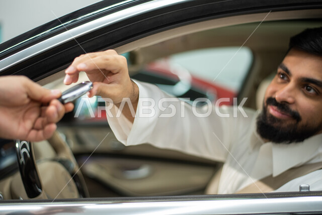 خدمات اصلاح وصيانة السيارات في الورشه, سائق عربي سعودي خليجي مبتسم يرتدي الثوب السعودي التقليدي يجلس في السياره,  يقوم بتسليم مفتاح السيارة لعامل الصيانة, ايماءات تدل على السعاده والرضى عن الخدمات الراقيه والمتميزه, مركز الصيانه وتصليح وسائل المواصلات 
