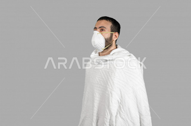 بورتريه لشاب عربي خليجي سعودي يرتدي ملابس الاحرام، ارتداء الكمامة الواقية، اتخاذ اجراءات الوقاية من فايروس كورونا (كوفيد-19)، ايماءات وجه ويدين مختلفة، خلفية بيضاء