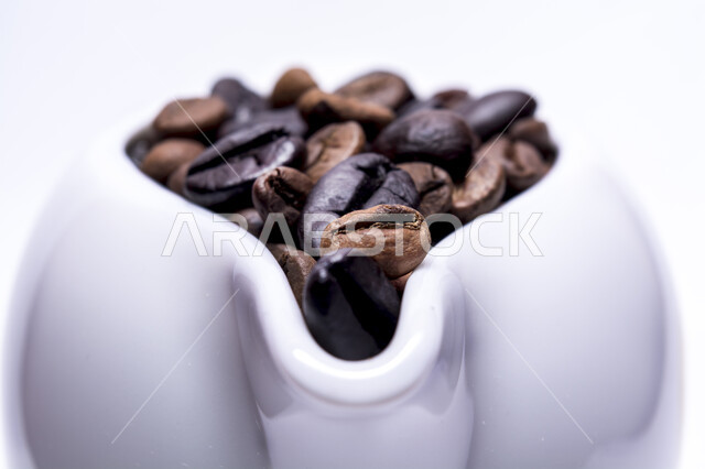 تصوير مقرب لكوب ابيض زجاجي مليئ بحبوب البن المحمص، حبوب القهوة الطازجة، بذور القهوة، مقاهي وكافيهات