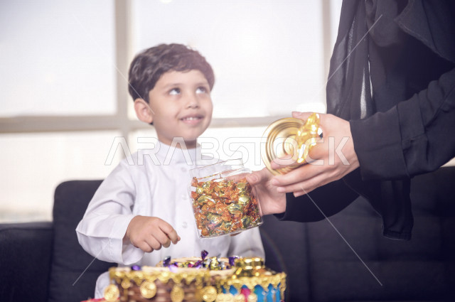 مشاركة رائعة لأم عربية خليجية سعودية مع ابنها في صباح يوم العيد تقوم بتقديم الحلوى له بإيماءات تدل على السعادة و الفرح ، ارتداء اللباس السعودي التقليدي ، العيدية ، القرقيعان ، احتفالات و مظاهر العيد ، قضاء أوقات عائلية سعيدة في العيد