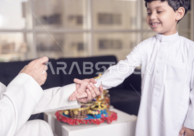 مشاركة رائعة لأب عربي خليجي سعودي مع ابنه في صباح يوم العيد ، تقديم العيدية بسعادة ، ارتداء اللباس السعودي التقليدي ، العيدية ، القرقيعان ، احتفالات و مظاهر العيد ، عطلة رسمية ، قضاء أوقات عائلية سعيدة في العيد